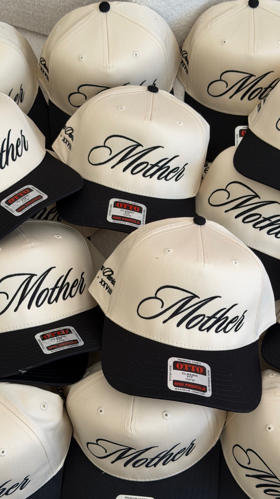Stack of cream and black 5-panel snapback hats with black Mother script embroidery on the front panel and Roman numeral side hit, custom embroidery by Colorblox Merch Co. in Gilbert, Arizona